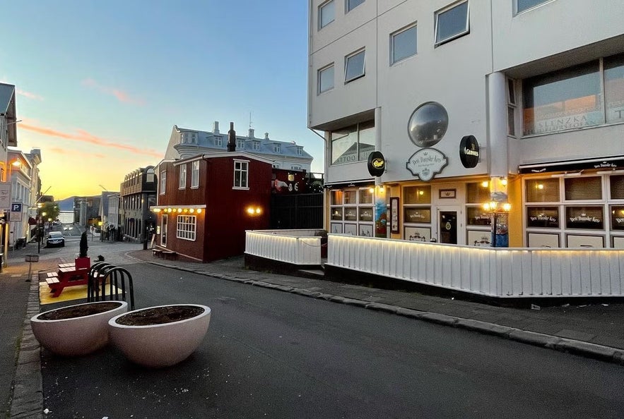A street in downtown Reykjavik at sunset with The Drunk Rabbit Irish Pub lit up beside other colorful buildings.