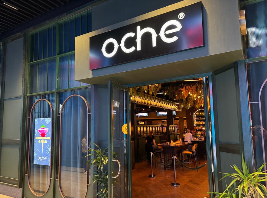 Entrance to Oche Reykjavik with open doors revealing a stylish interior where guests enjoy drinks and games.