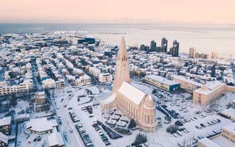 Snow-covered Reykjavik with Hallgrimskirkja Church in the city center and harbor in the distance.