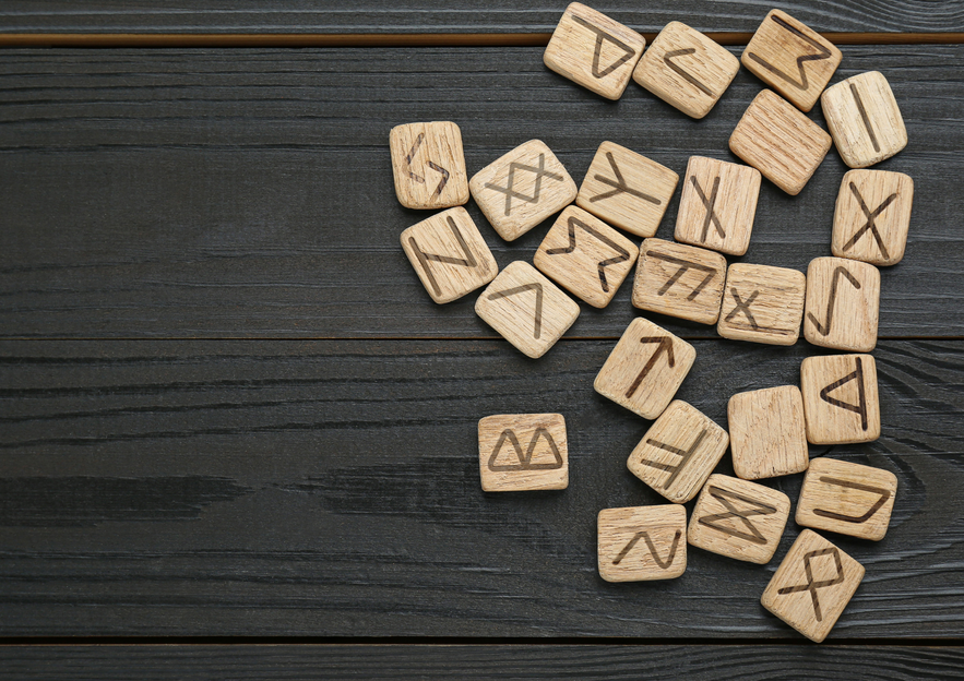 Wooden tiles engraved with Icelandic runes on a dark table, used for divination and ancient Norse writing