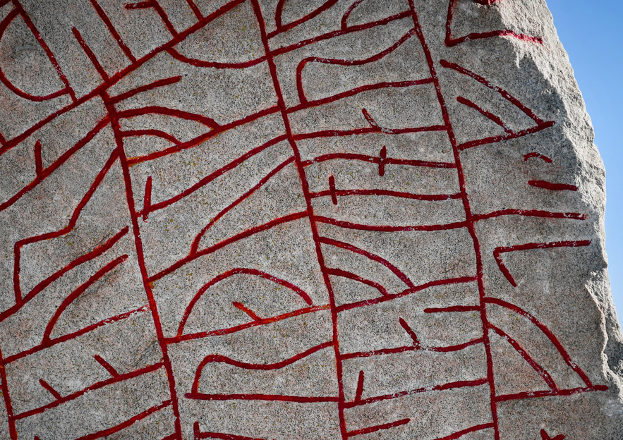 Red carvings of ancient Icelandic runes etched into a stone surface