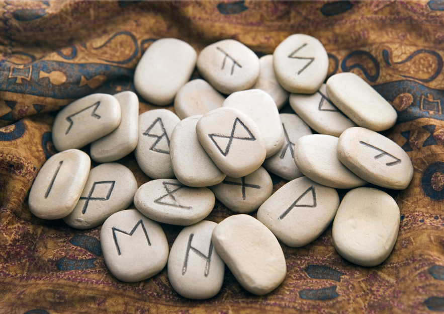 Smooth stones engraved with Icelandic runes used for divination, resting on patterned fabric