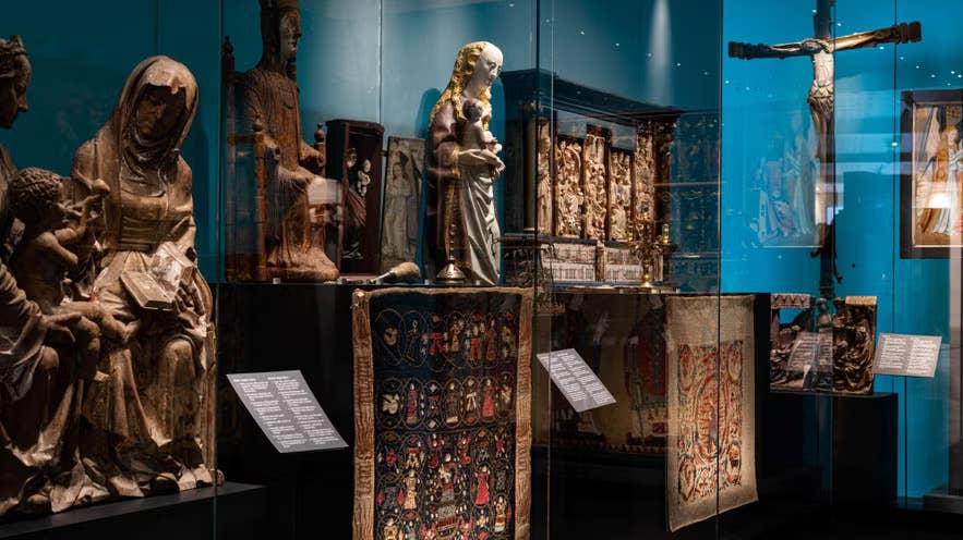 Mittelalterliche religiöse Kunst im Nationalmuseum von Island mit Holzskulpturen und Wandteppichen.