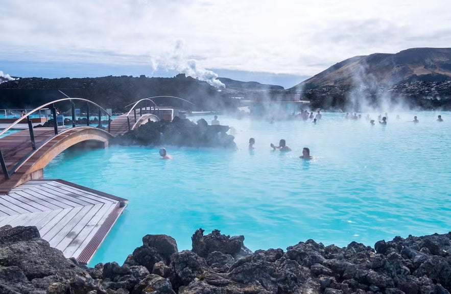 People at the Blue Lagoon with the in water bar in the background and bridges on the edge