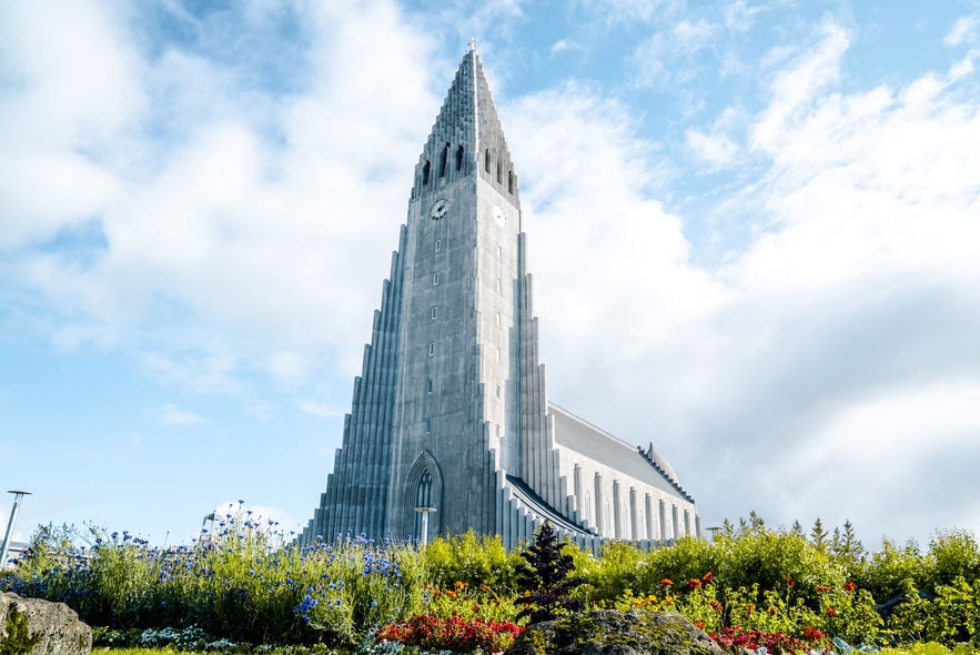 Hallgrimskirkja church in Reykjavik, Iceland, under a clear sky with colorful flowers in the foreground.