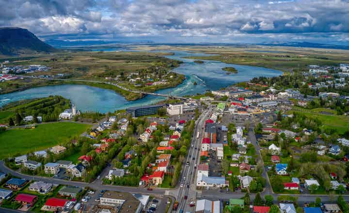 Вид с воздуха на город Селфосс на юге Исландии: хорошо видна река Ольфуса, мост Ольфусарбру и живописные сельские окрестности.