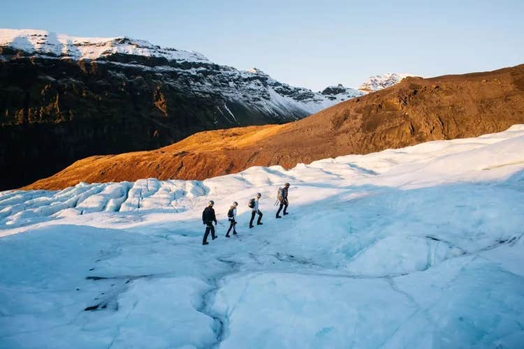 Group of hikers walking on Falljokull glacier in Skaftafell under winter sunlight.