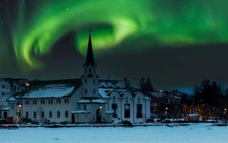 Fríkirkjan-kirkko Reykjavikissa kylpee revontulten pehmeässä hohteessa.
