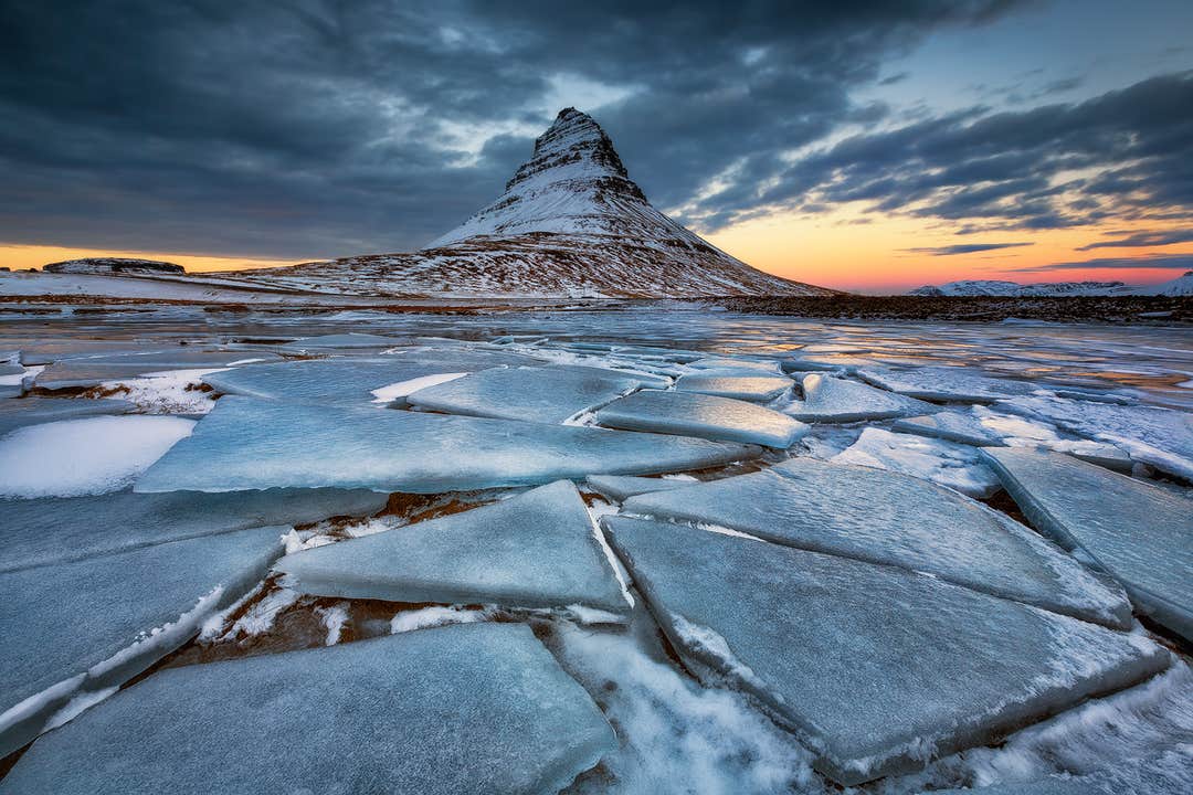 Kirkjufell-vuori talvella jäätyneen rantaviivan äärellä auringonlaskun aikaan Snæfellsnesin niemimaalla Islannissa