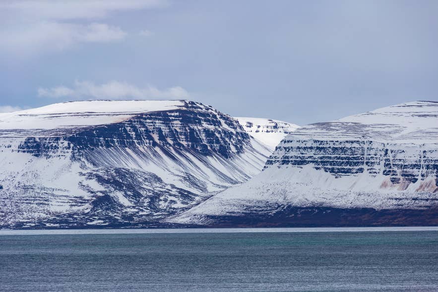 Schneebedeckte Berge und Küstenklippen nahe dem Drangajökull-Gletscher in den Westfjorden Islands.