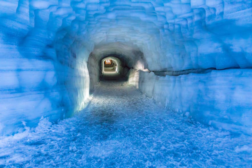 Im Inneren des künstlichen Eistunnels des Langjökull-Gletschers in Westisland, beleuchtet von sanftem blauem Licht.