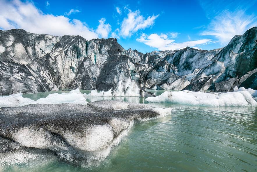 Icebergs and meltwater lagoon at the base of Myrdalsjokull Glacier in South Iceland under clear blue skies.