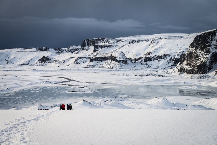 Group of hikers walking across a snowy landscape near Eyjafjallajokull Glacier in South Iceland.