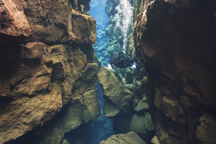 Diver exploring the deep rock formations of Silfra Fissure in Thingvellir National Park, Iceland.