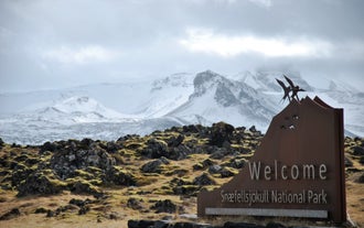 Entrance sign to Snaefellsjokull National Park surrounded by lava rocks.