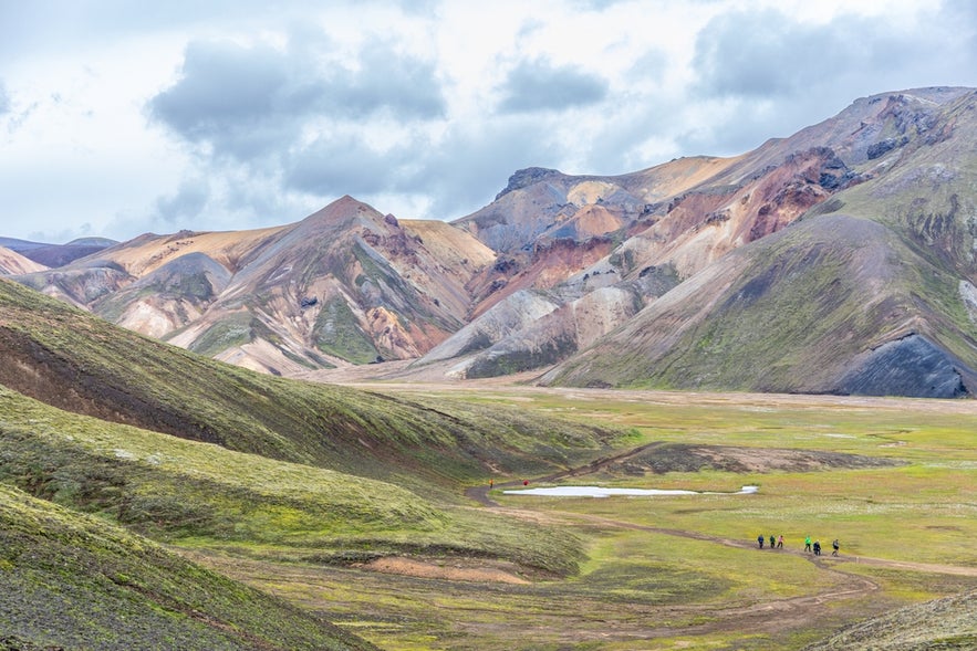 Hikers on a trail near Brennisteinsalda Mountain in Landmannalaugar, surrounded by colorful rhyolite slopes in Iceland.