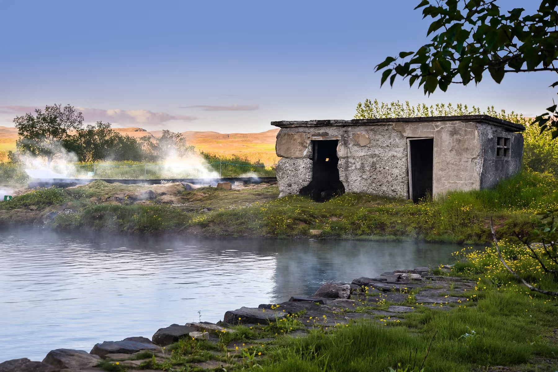 The Secret Lagoon in Fludir, Iceland’s oldest natural swimming pool, surrounded by geothermal steam.