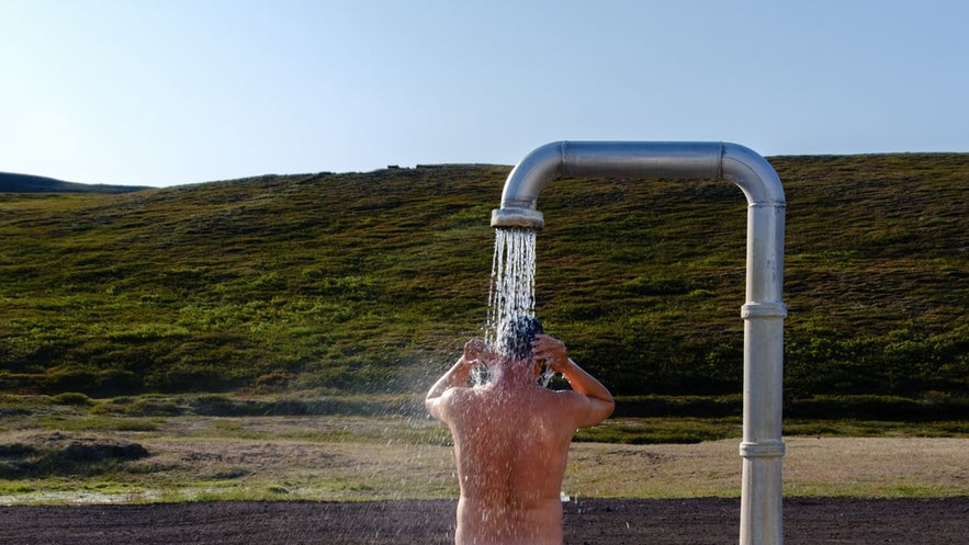 Icelander showering outdoors before entering a geothermal hot spring, following Iceland’s bathing etiquette.