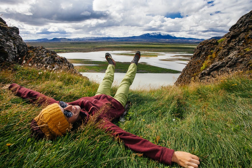 Icelander relaxing on grassy cliffs enjoying scenic views of rivers and mountains in North Iceland.