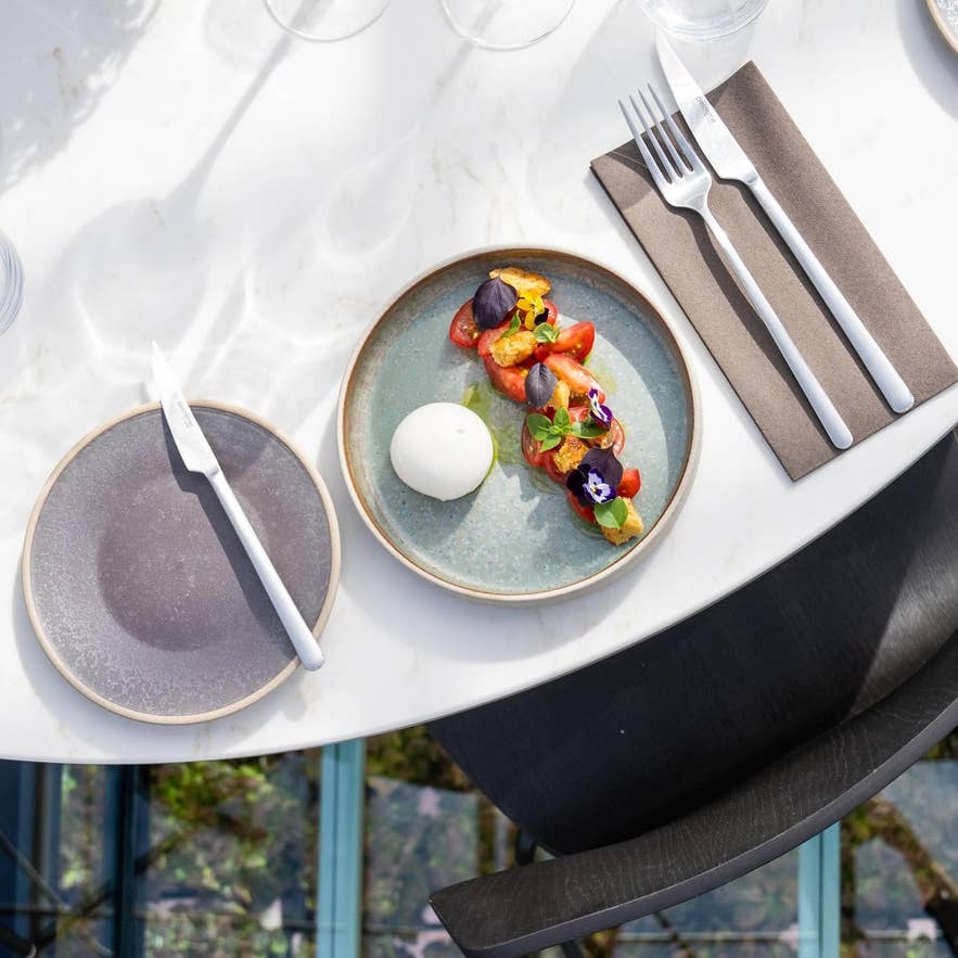 จานอาหารกูร์เมต์มะเขือเทศสด บูราต้า และดอกไม้กินได้ ที่ร้าน Sól Restaurant ในฮาฟนาร์ฟยอร์ดูร์ ไอซ์แลนด์