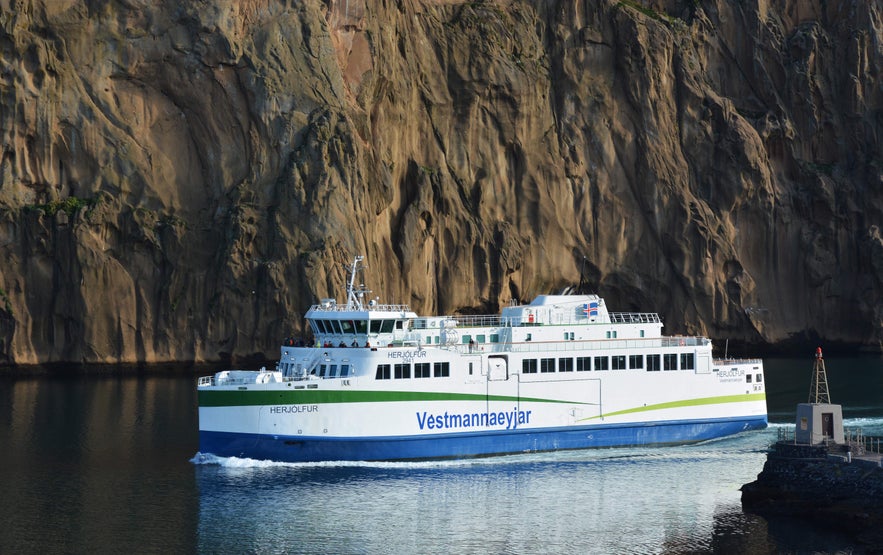Herjolfur ferry arriving at Heimaey Island in the Westman Islands, Iceland, with volcanic cliffs in the background.