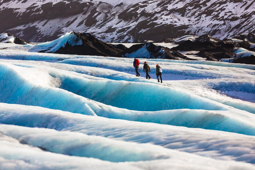 Excursionistas explorando las formaciones de hielo azul del glaciar S&oacute;lheimaj&ouml;kull en el sur de Islandia durante una caminata guiada.