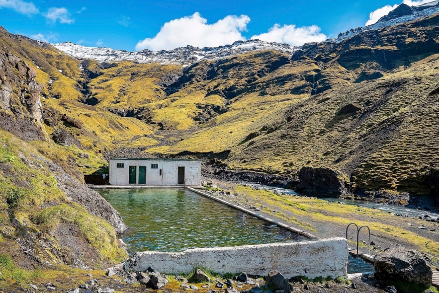 Seljavallalaug geothermal swimming pool in Iceland surrounded by green mountain slopes on the South Coast.