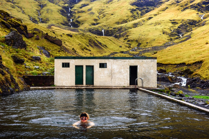 Person swimming in Seljavallalaug geothermal pool in Iceland.