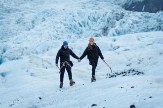 Couple hiking hand in hand on Vatnajokull Glacier with ice axes and crampons.