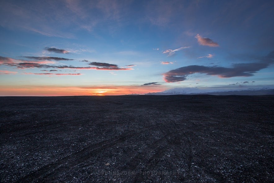 Sunset over Sólheimasandur black sand plain in South Iceland with colorful clouds and distant mountains