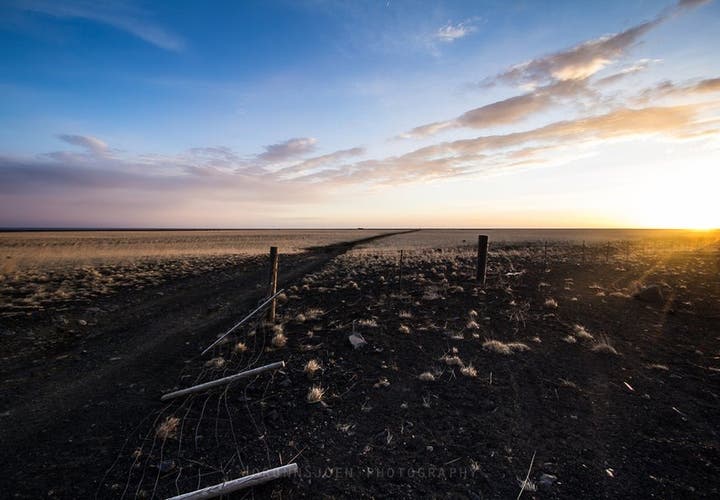 Sunrise over an open gravel road on Sólheimasandur plain in South Iceland with golden light and blue sky