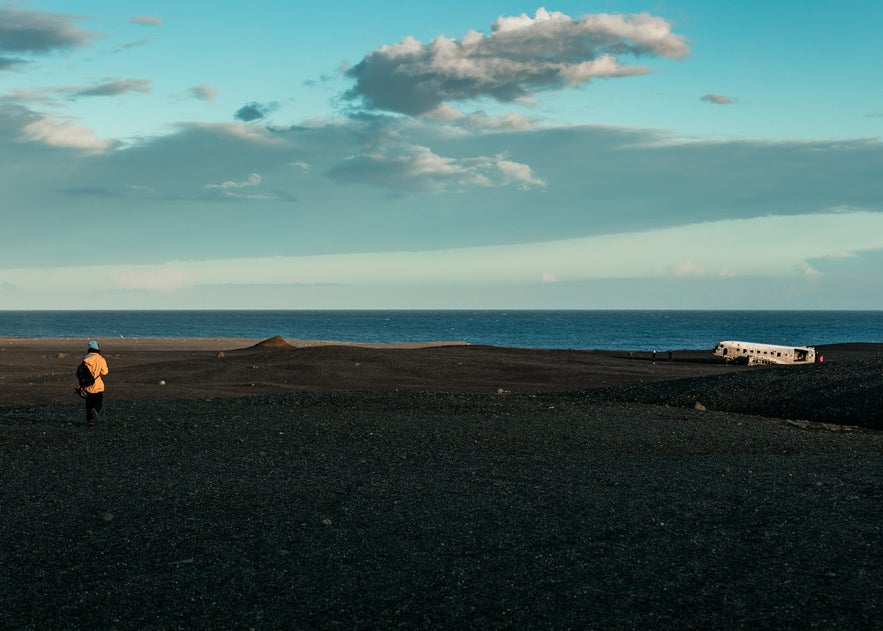 A person walking toward the DC3 Plane Wreck on Solheimasandur Beach.