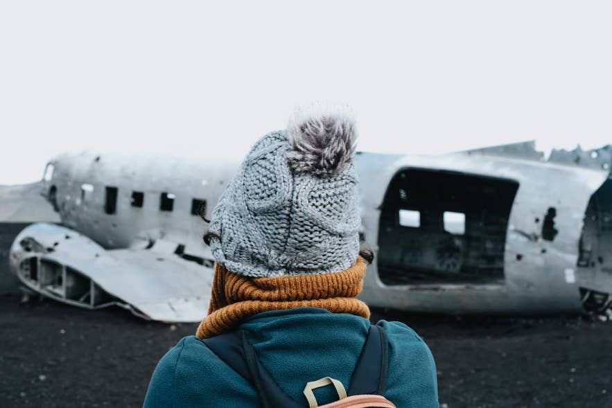 Visiteur admirant la célèbre épave du DC3 à Solheimasandur sur la plage de sable noir d'Islande.