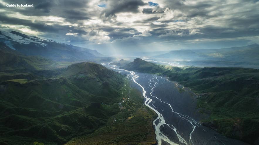 Une rivière traverse la vallée de Thorsmork, entourée de verdure luxuriante sous un ciel nuageux.