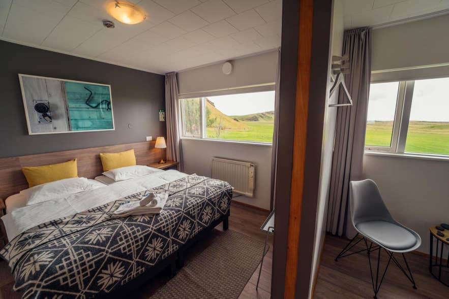 Chambre accueillante avec un lit et une fenêtre donnant sur un champ, située au Farmhouse Lodge près de Solheimasandur.