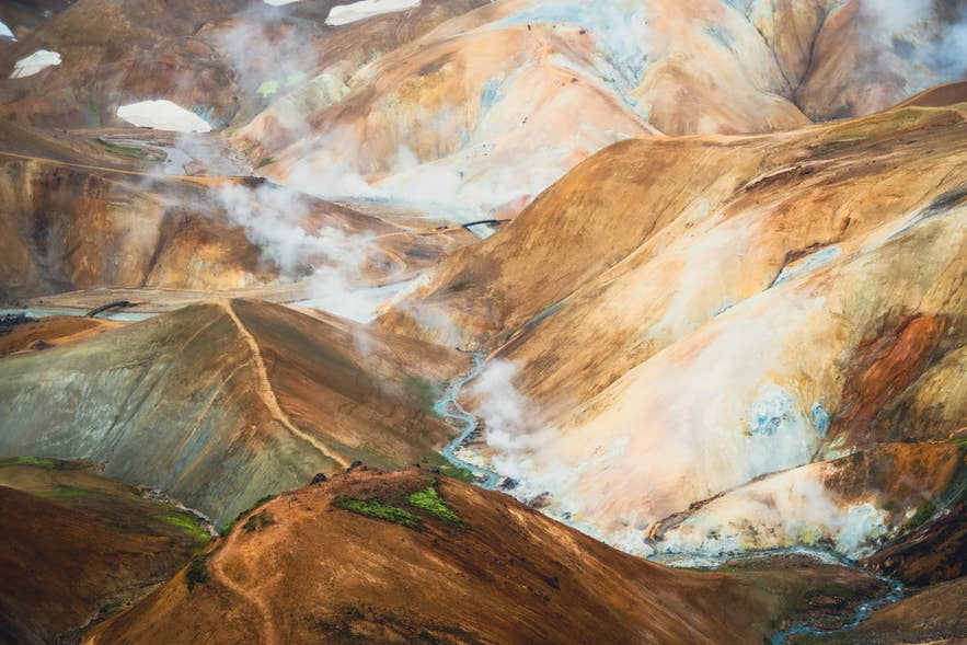 Dampf erhebt sich über die bunten Rhyolith-Hügel der Kerlingarfjöll-Berge – ein geothermales Wunder unter Islands Naturwundern.
