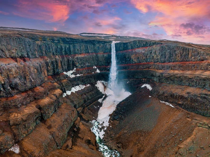 Der Hengifoss-Wasserfall stürzt über rot gestreifte Klippen in Ostisland – ein beeindruckendes Beispiel für Islands Naturwunder
