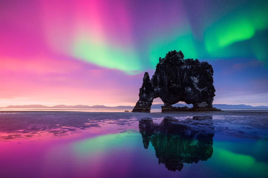 Der Hvitserkur-Fels ragt unter leuchtenden Nordlichtern empor – ein atemberaubender Anblick, der die Naturschönheit Islands einfängt.