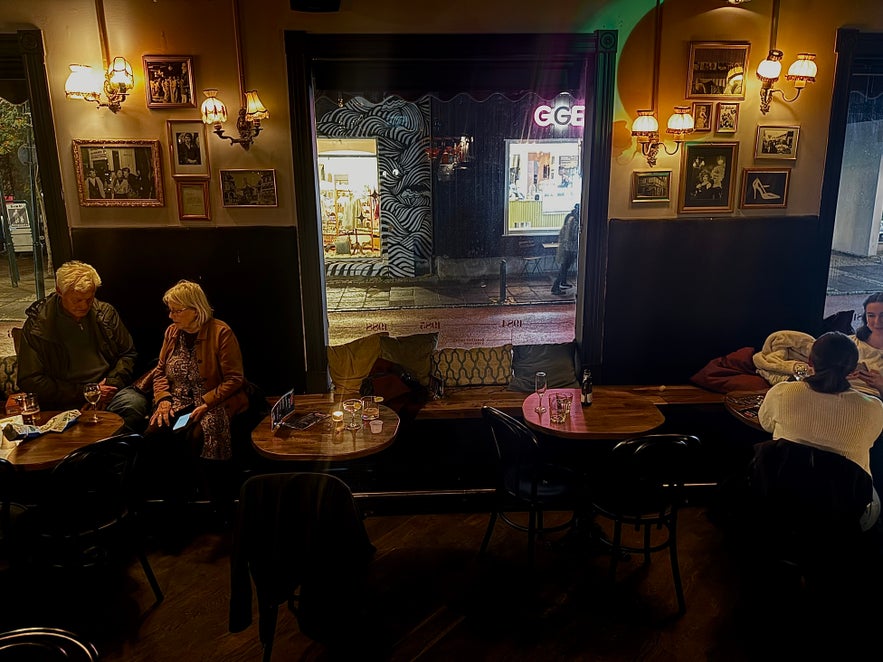 Guests sitting by the window at 22 Bar, surrounded by framed vintage photos and soft golden lighting.