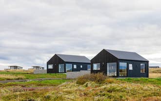 Modern black cabins at Torfa Lodge sit on open land in the Golden Circle with privacy and mountain views.