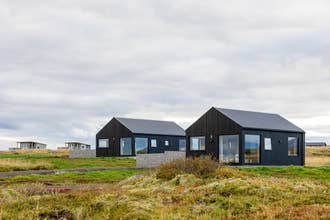Modern black cabins at Torfa Lodge sit on open land in the Golden Circle with privacy and mountain views.