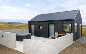 Private patio with a hot tub and chairs at Torfa Lodge offers outdoor relaxation after exploring Iceland.