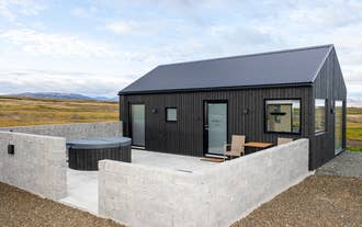 Private patio with a hot tub and chairs at Torfa Lodge offers outdoor relaxation after exploring Iceland.