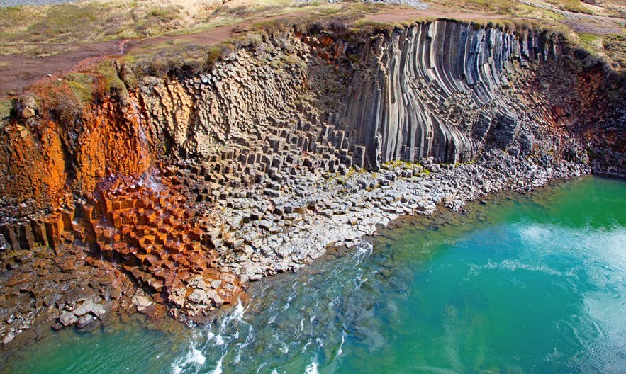 Bunte Basaltsäulen und türkisfarbenes Wasser prägen den Studlagil-Canyon, eine der eindrucksvollsten Naturattraktionen Islands
