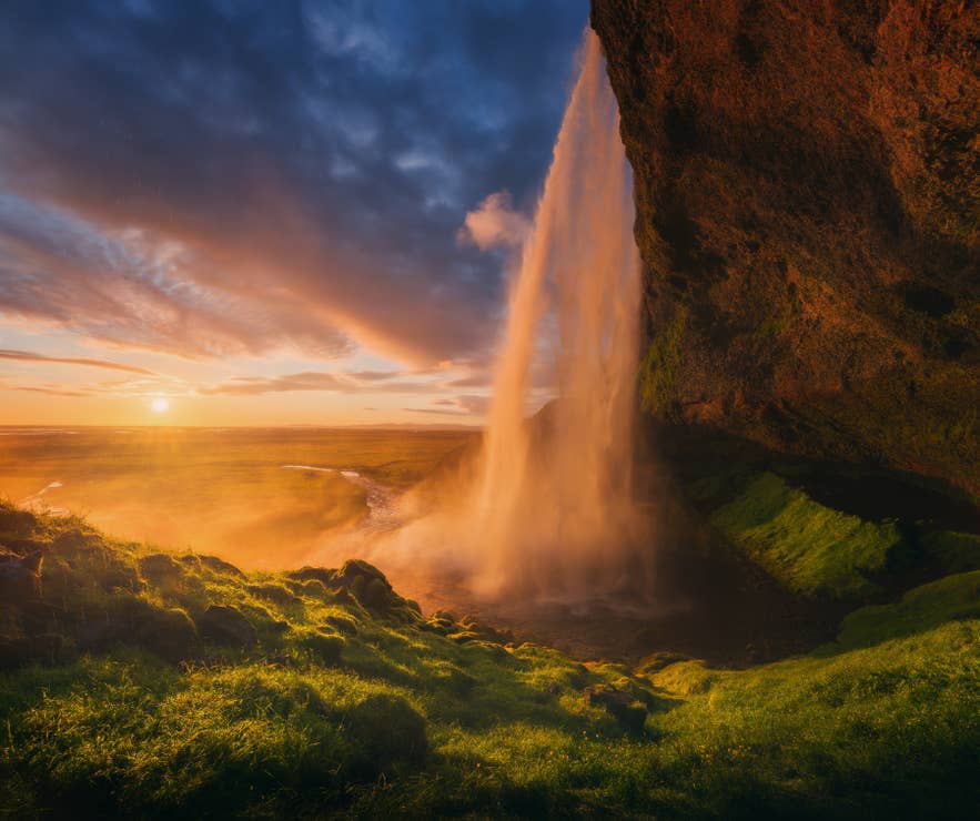 Das Licht der untergehenden Sonne strahlt durch den Seljalandsfoss, einen der atemberaubendsten Wasserfälle Islands.
