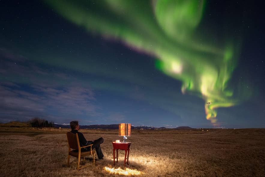 A man sitting in a chair watching the northern lights in Iceland, enjoying the view safely during clear weather.