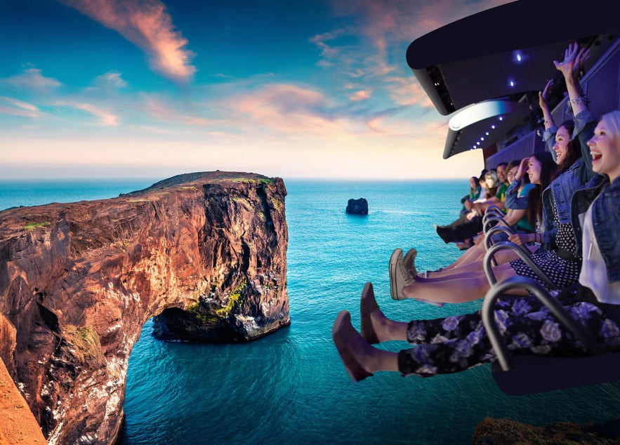 Visitors on the FlyOver Iceland ride glide above Iceland’s cliffs and ocean, simulating flight over dramatic coastal scenery.