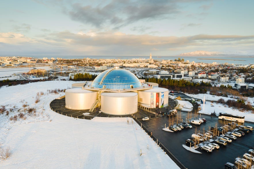 Perlan Museum and its glass dome overlooking snow-covered Reykjavik with Mount Esja in the distance.