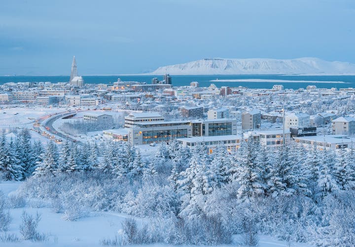 Snow-covered Reykjavik glows under soft winter light with Hallgrimskirkja Church and Mount Esja visible in the background.