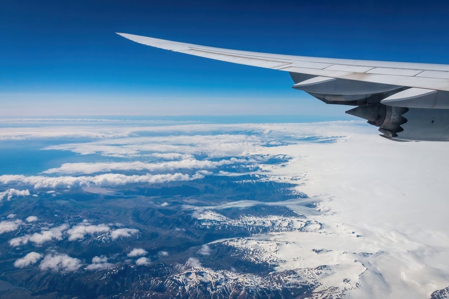 Airplane flying over Iceland’s glaciers and volcanic peaks, capturing the view for travelers on a layover or stopover in Iceland.